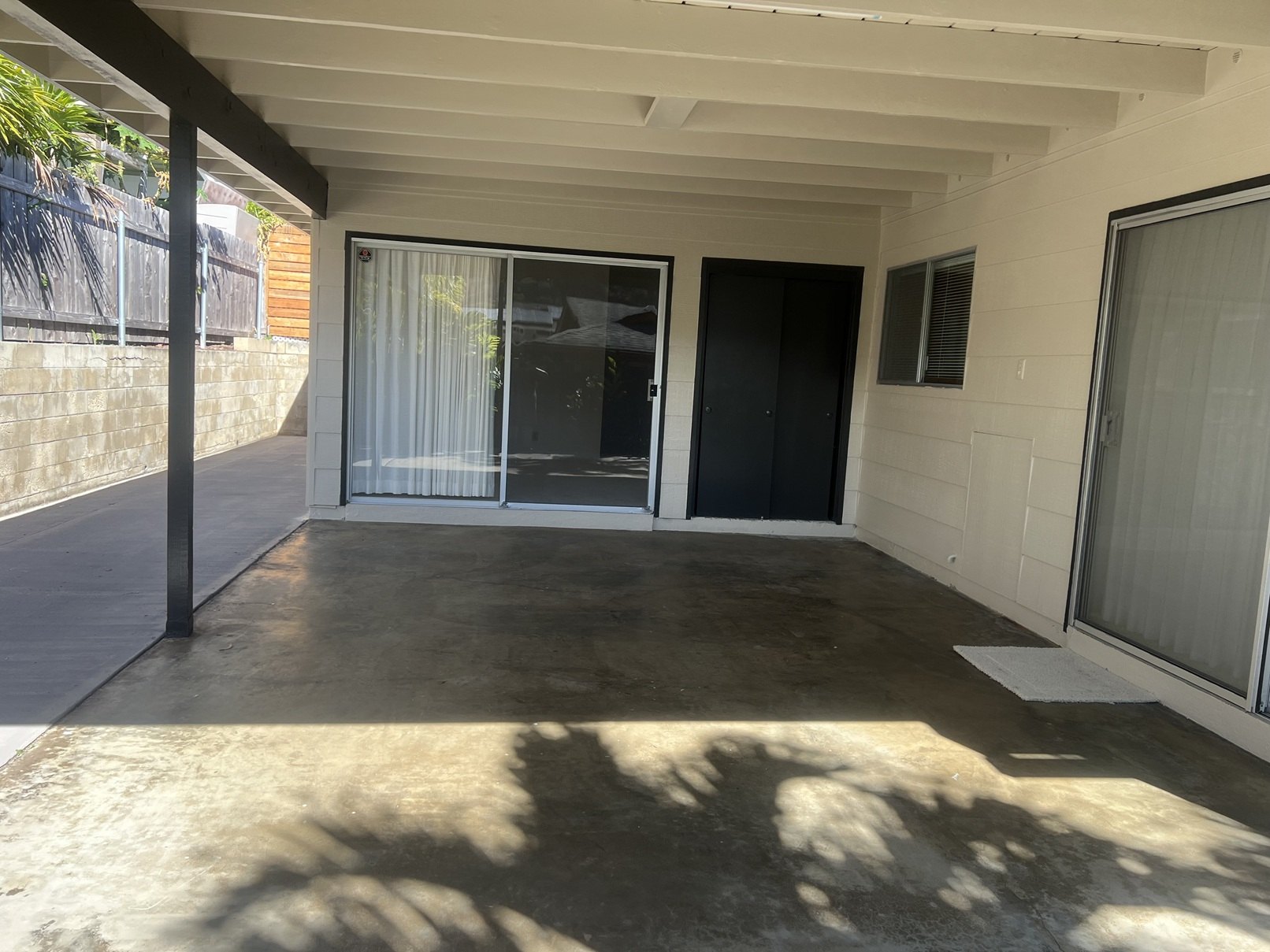 A patio area with a black door and a sliding glass door.